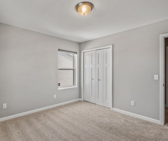 unfurnished bedroom featuring carpet floors, a closet, and baseboards