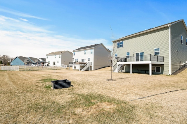 back of property featuring a lawn, a deck, fence, a residential view, and stairs