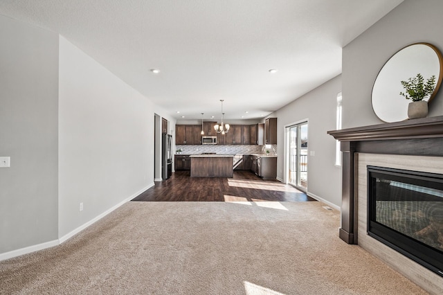 20147 79th Ave, Corcoran, MN 55340 - unfurnished living room featuring dark colored carpet, recessed lighting, a chandelier, baseboards, and a glass covered fireplace