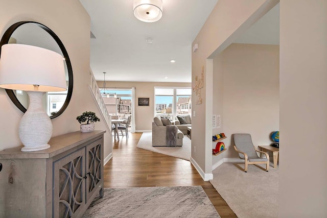 hallway featuring baseboards, recessed lighting, wood finished floors, and a notable chandelier