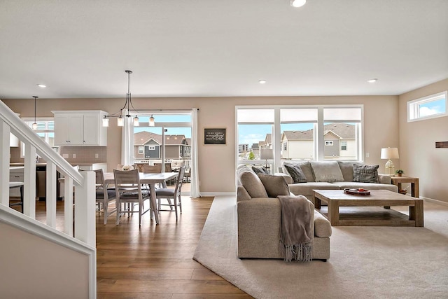 living area with recessed lighting, stairs, baseboards, and wood finished floors