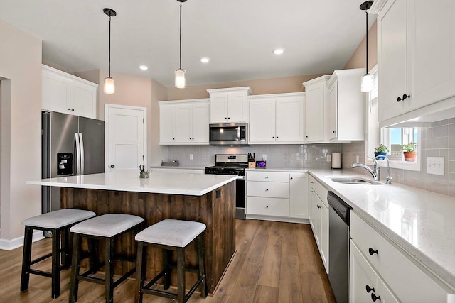 kitchen with a kitchen island, dark wood-style flooring, a sink, white cabinets, and stainless steel appliances