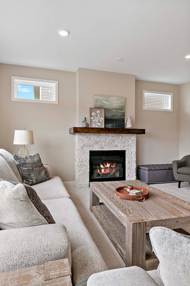 living room with recessed lighting, a stone fireplace, and plenty of natural light