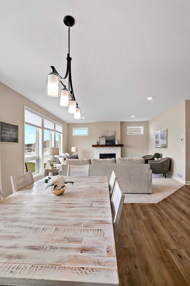 dining space featuring visible vents, recessed lighting, baseboards, wood finished floors, and a lit fireplace