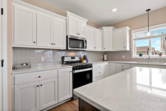 kitchen with backsplash, white cabinetry, appliances with stainless steel finishes, and a sink