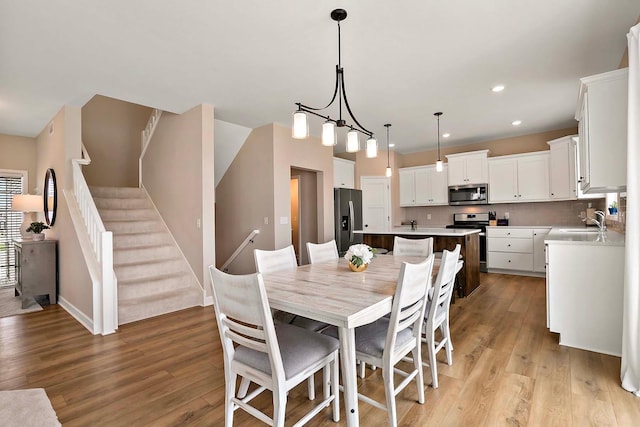 dining space with light wood-style floors, baseboards, stairway, and recessed lighting