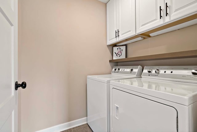 washroom featuring cabinet space, baseboards, and washer and clothes dryer