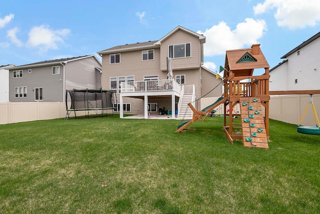 back of property with a trampoline, a fenced backyard, a playground, a patio, and a lawn