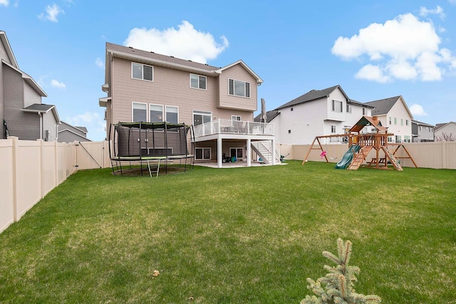 back of property featuring a trampoline, a residential view, a fenced backyard, a playground, and stairs