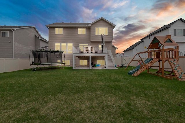 back of property at dusk featuring stairway, a playground, a fenced backyard, and a trampoline