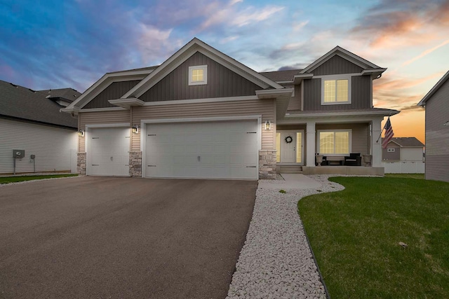 craftsman-style house with a front lawn, stone siding, a garage, board and batten siding, and driveway
