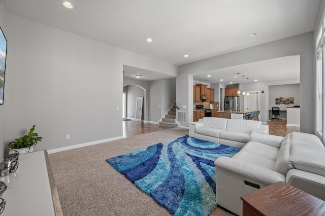 living area with arched walkways, baseboards, recessed lighting, and light colored carpet