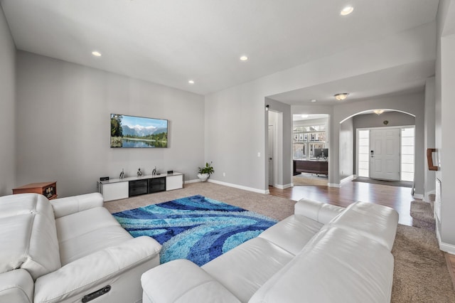 carpeted living area featuring arched walkways, baseboards, and recessed lighting