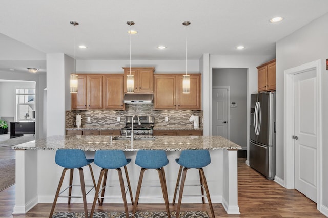 kitchen with backsplash, stainless steel appliances, a breakfast bar, and dark wood-style floors