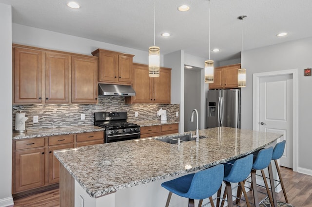 kitchen with tasteful backsplash, wood finished floors, a sink, stainless steel appliances, and extractor fan