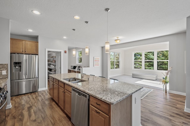kitchen with a sink, appliances with stainless steel finishes, dark wood-style floors, and open floor plan