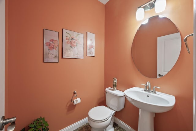 half bathroom featuring toilet and baseboards
