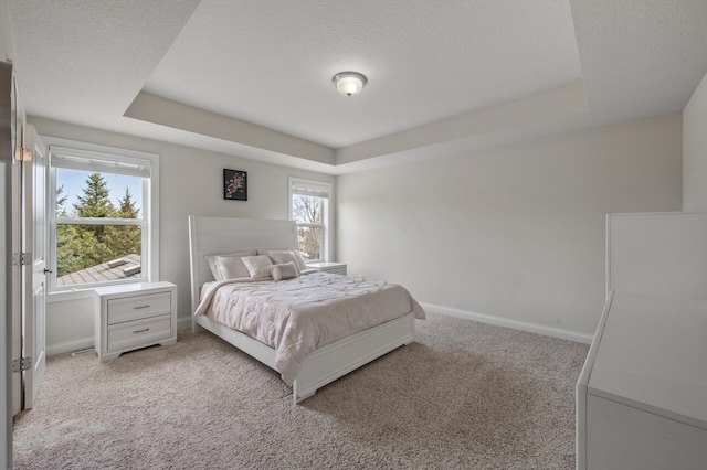 bedroom featuring a raised ceiling, baseboards, light carpet, and a textured ceiling