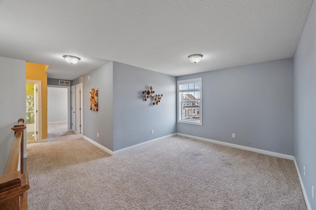 carpeted spare room with baseboards, a textured ceiling, and visible vents