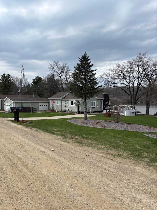 view of front of property with dirt driveway, a front yard, an attached garage, and a residential view