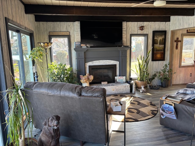 living room with wooden walls, beamed ceiling, wood finished floors, a brick fireplace, and wood ceiling