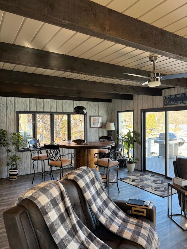 living room with beamed ceiling, wooden walls, and wood finished floors