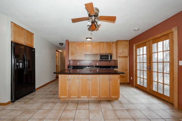 kitchen featuring dark countertops, light tile patterned floors, stainless steel microwave, baseboards, and black fridge