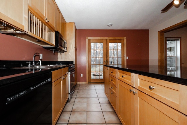 kitchen featuring dark countertops, a ceiling fan, a sink, light tile patterned floors, and appliances with stainless steel finishes