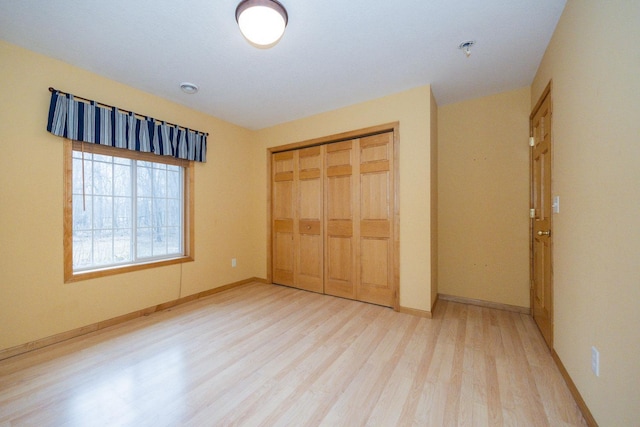 unfurnished bedroom featuring baseboards, wood finished floors, and a closet