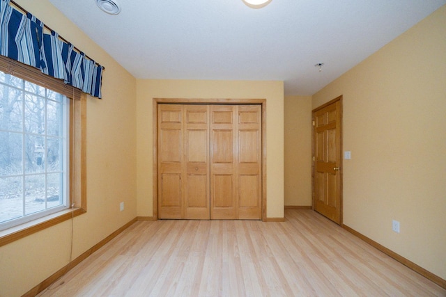 unfurnished bedroom with baseboards, light wood finished floors, and a closet