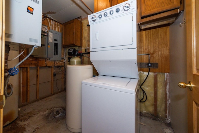 laundry area featuring stacked washer and clothes dryer, water heater, electric panel, and cabinet space