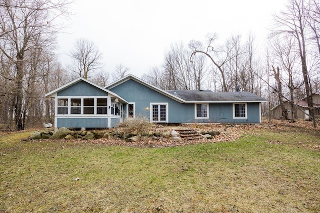 back of property with a sunroom and a yard