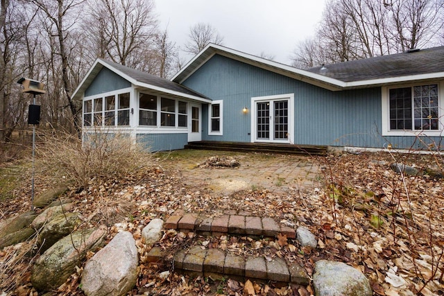 back of property with a sunroom and a shingled roof