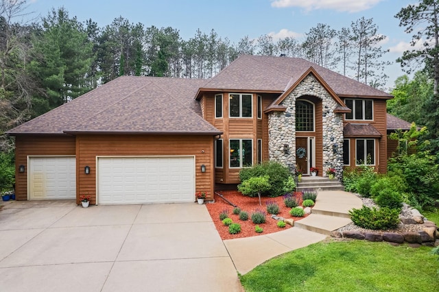 17 Lake Ct, North Oaks, MN 55127 - view of front facade featuring an attached garage, concrete driveway, stone siding, and roof with shingles
