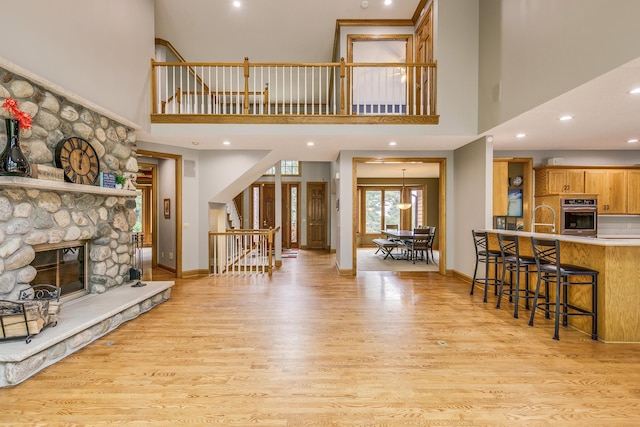 17 Lake Ct, North Oaks, MN 55127 - living room featuring light wood finished floors, a high ceiling, recessed lighting, a stone fireplace, and stairs