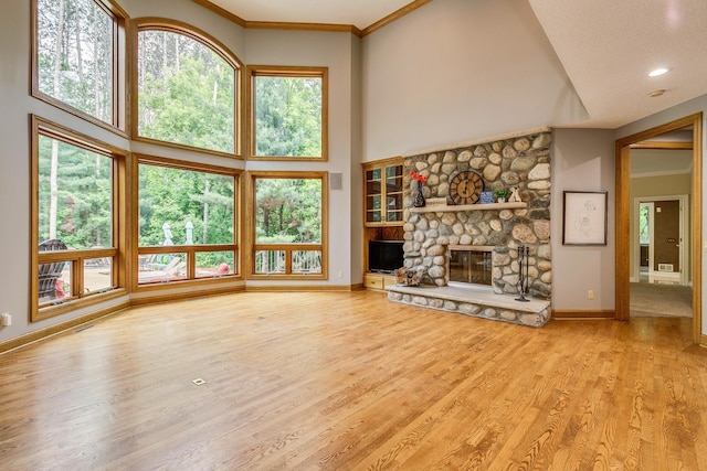17 Lake Ct, North Oaks, MN 55127 - unfurnished living room featuring wood finished floors, plenty of natural light, a stone fireplace, a high ceiling, and crown molding