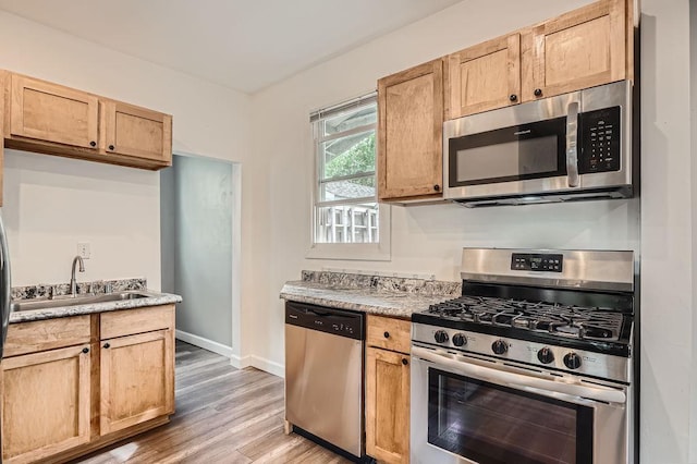 1907 University Ave NE, Minneapolis, MN 55418 - kitchen featuring stainless steel appliances, a sink, light wood-type flooring, baseboards, and light countertops