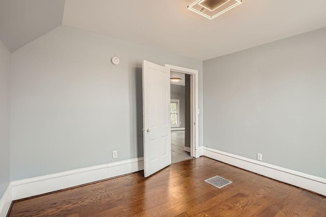 1907 University Ave NE, Minneapolis, MN 55418 - spare room featuring baseboard heating, wood finished floors, baseboards, a smoke detector, and vaulted ceiling