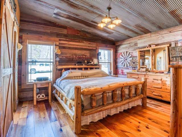 23660 Cap Endres Rd NE, Cass Lake, MN 56633 - bedroom featuring lofted ceiling, a chandelier, wooden walls, and hardwood / wood-style flooring