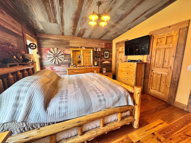 23660 Cap Endres Rd NE, Cass Lake, MN 56633 - bedroom featuring wooden walls, lofted ceiling, wood finished floors, and a chandelier