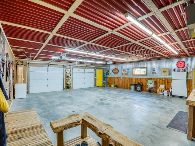 23660 Cap Endres Rd NE, Cass Lake, MN 56633 - garage featuring freestanding refrigerator, a garage door opener, and wood walls