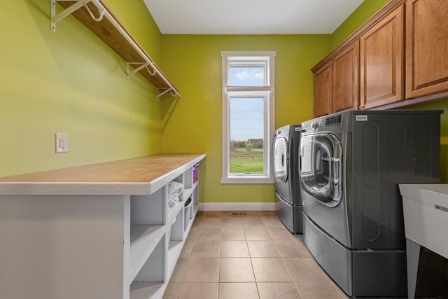 6570 Chester Ave, Webster Twp, MN 55057 - laundry area with light tile patterned floors, baseboards, cabinet space, and washing machine and clothes dryer
