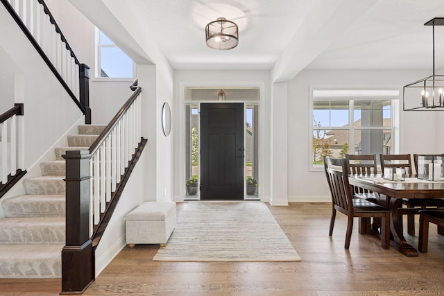 entryway with a chandelier, stairs, baseboards, and plenty of natural light