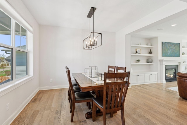 dining room with an inviting chandelier, plenty of natural light, light wood-style flooring, and baseboards
