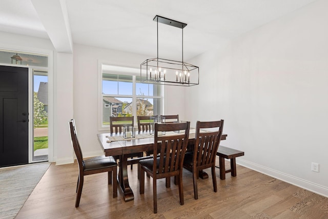 dining space with baseboards, an inviting chandelier, and wood finished floors