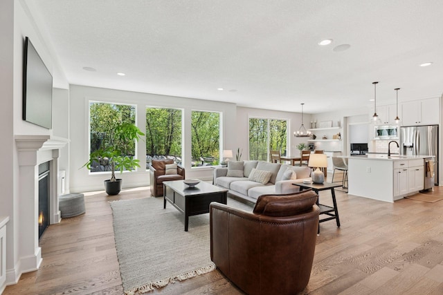 living area with light wood finished floors, a glass covered fireplace, and recessed lighting