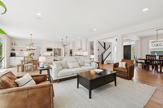 living room with stairs, a notable chandelier, and a healthy amount of sunlight