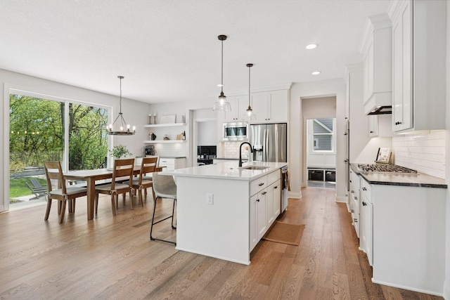 kitchen with a sink, tasteful backsplash, light wood-style floors, and appliances with stainless steel finishes