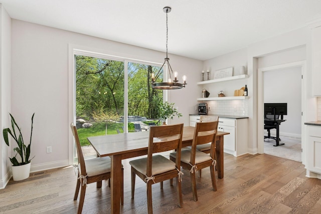 dining area with light wood finished floors, a chandelier, and baseboards