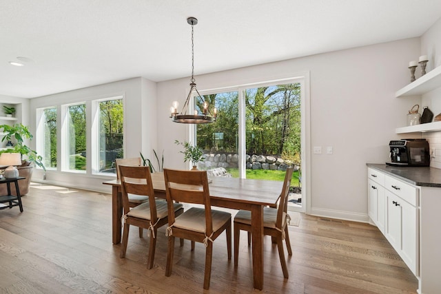 dining space featuring a wealth of natural light, light wood-style flooring, baseboards, and a notable chandelier